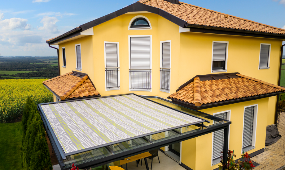 Ausgefahrene Markise über einer Terrassenüberdachung an einem mediterranen Haus