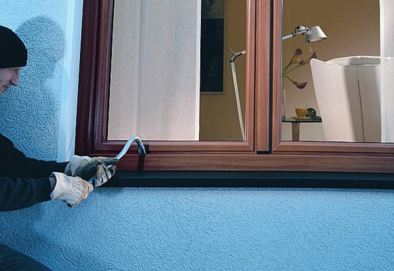 Person versucht mit Werkzeug ein Fenster aufzubrechen