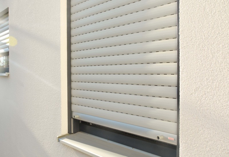 Rolladen in fast geschlossener Position in verputzter Fassade