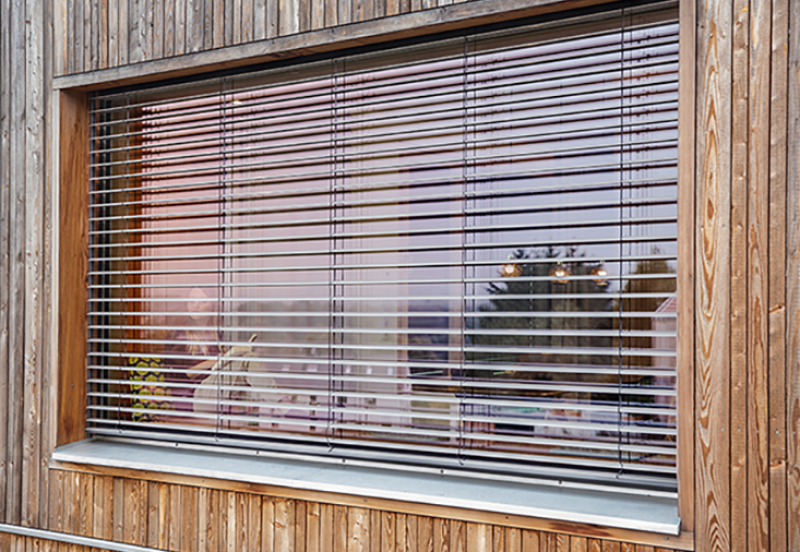 Raffstore halb geöffnet eingebaut in einer Holzfassade