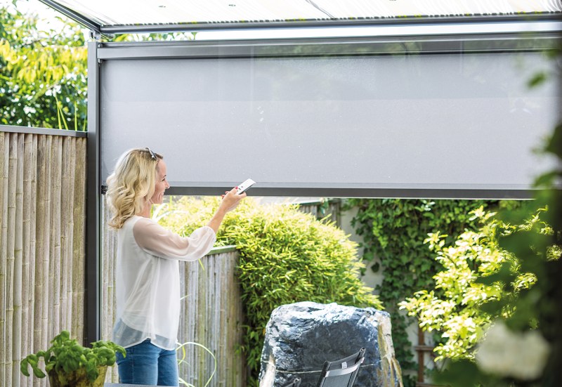 Person verschließt die Beschattung zum Schutz vor Sonne und Einblicken auf die Terrasse