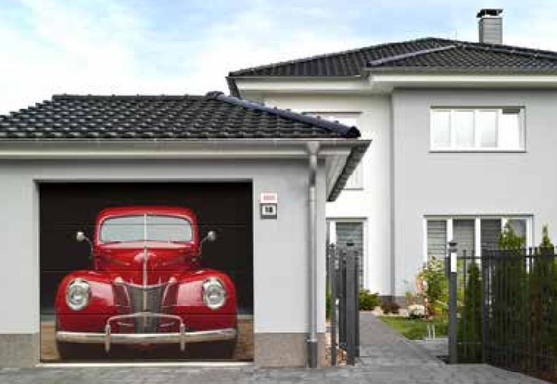 Geöffnetes Garagentor mit einem Oldtimer in der Garage im Hintergrund ein Einfamilienhaus