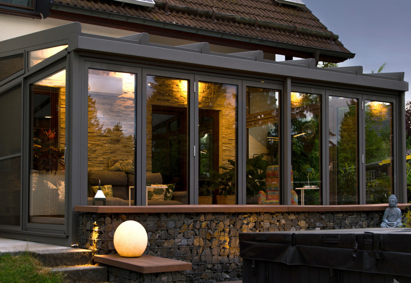 Wintergarten mit breiter Faltanlage in abendlichen Licht im Herbst