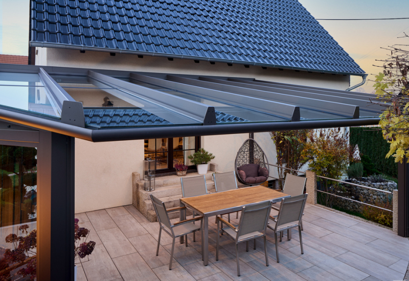 Terrassenüberdachung angepasst an die Hausform über einer Sitzgruppe