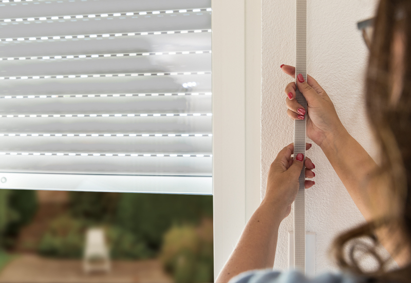 Person bedient einen manuell angetriebenen Rollladen und öffnet ihn